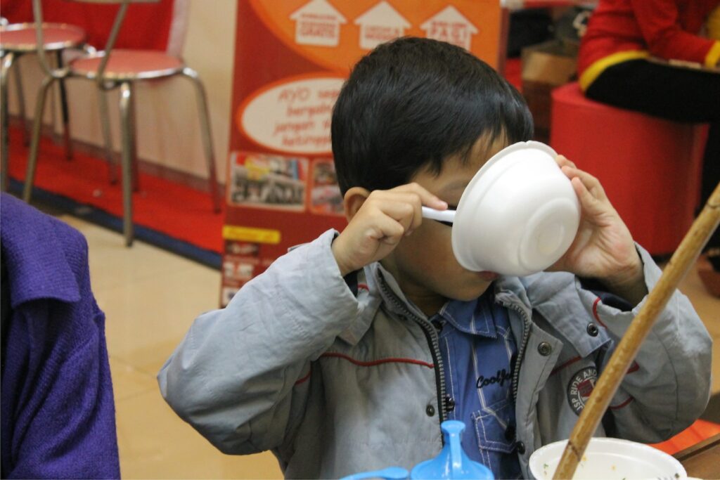 boy in gray zip up jacket drinking from white ceramic mug